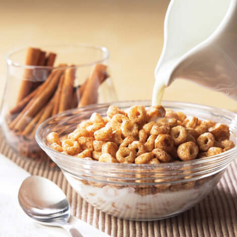 Delicious protein cereal in a bowl topped with milk and cinnamon sticks, perfect for a healthy breakfast.